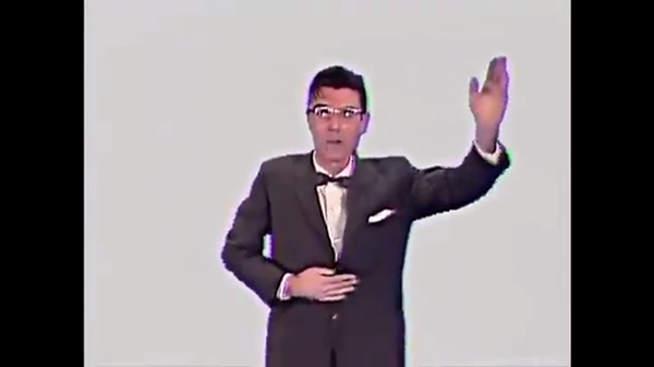 Screenshot, "Once in a Lifetime." Byrne begins his choreography with the proselytizer pose.